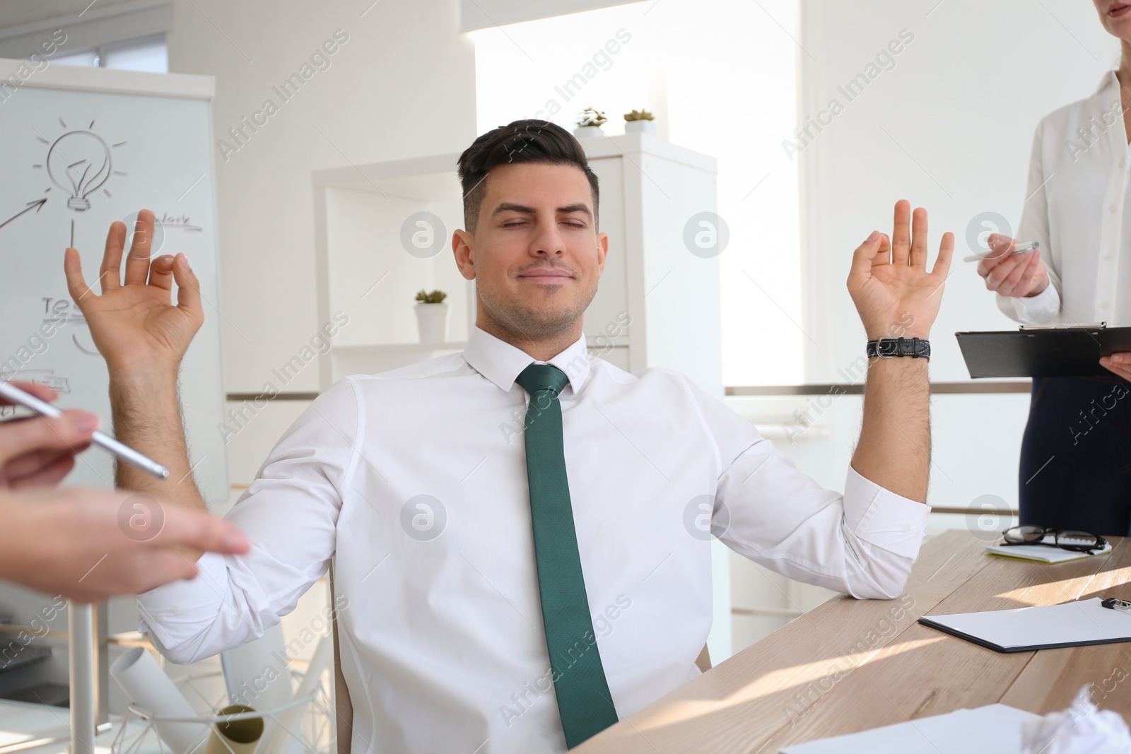 Photo of Businessman meditating at workplace in office. Stress relieving exercise