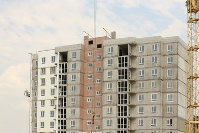 Photo of Yellow construction crane near unfinished building outdoors