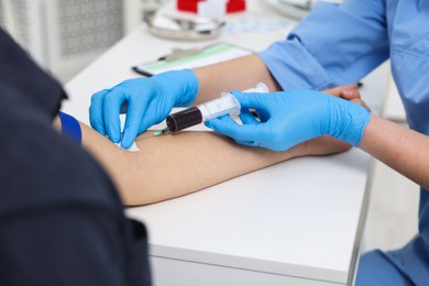 Laboratory testing. Doctor taking blood sample from patient at white table in hospital, closeup