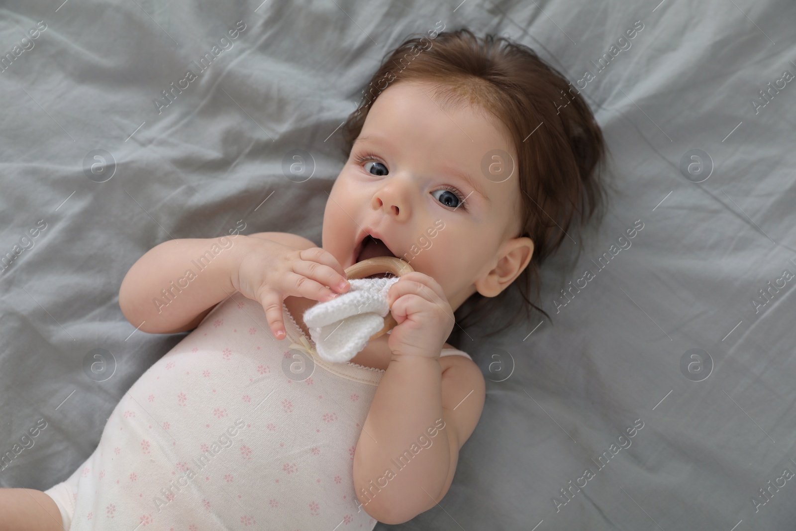 Photo of Cute little baby with toy on bed, top view