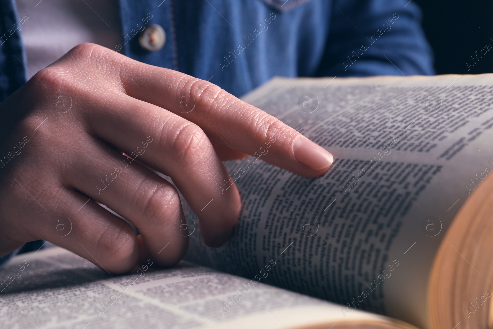 Photo of Woman reading holy Bible on black background, closeup