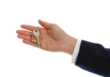 Photo of Real estate agent holding house key with trinket on white background, closeup