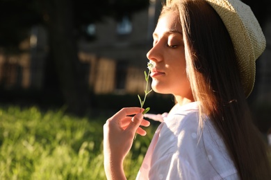 Photo of Young woman with flower outdoors on sunny day, space for text