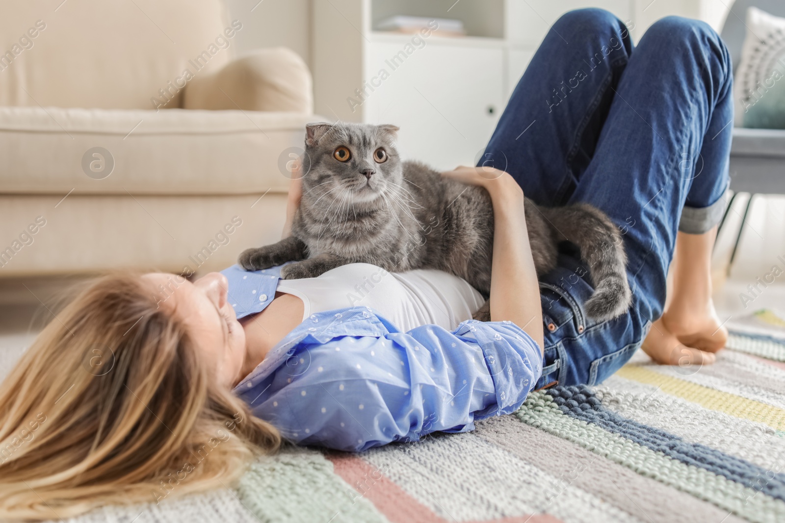 Photo of Young woman with her cute pet cat on floor at home