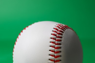 Photo of One baseball ball with stitches on green background, closeup