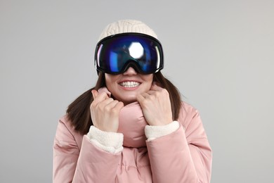 Winter sports. Happy woman with snowboard goggles on grey background