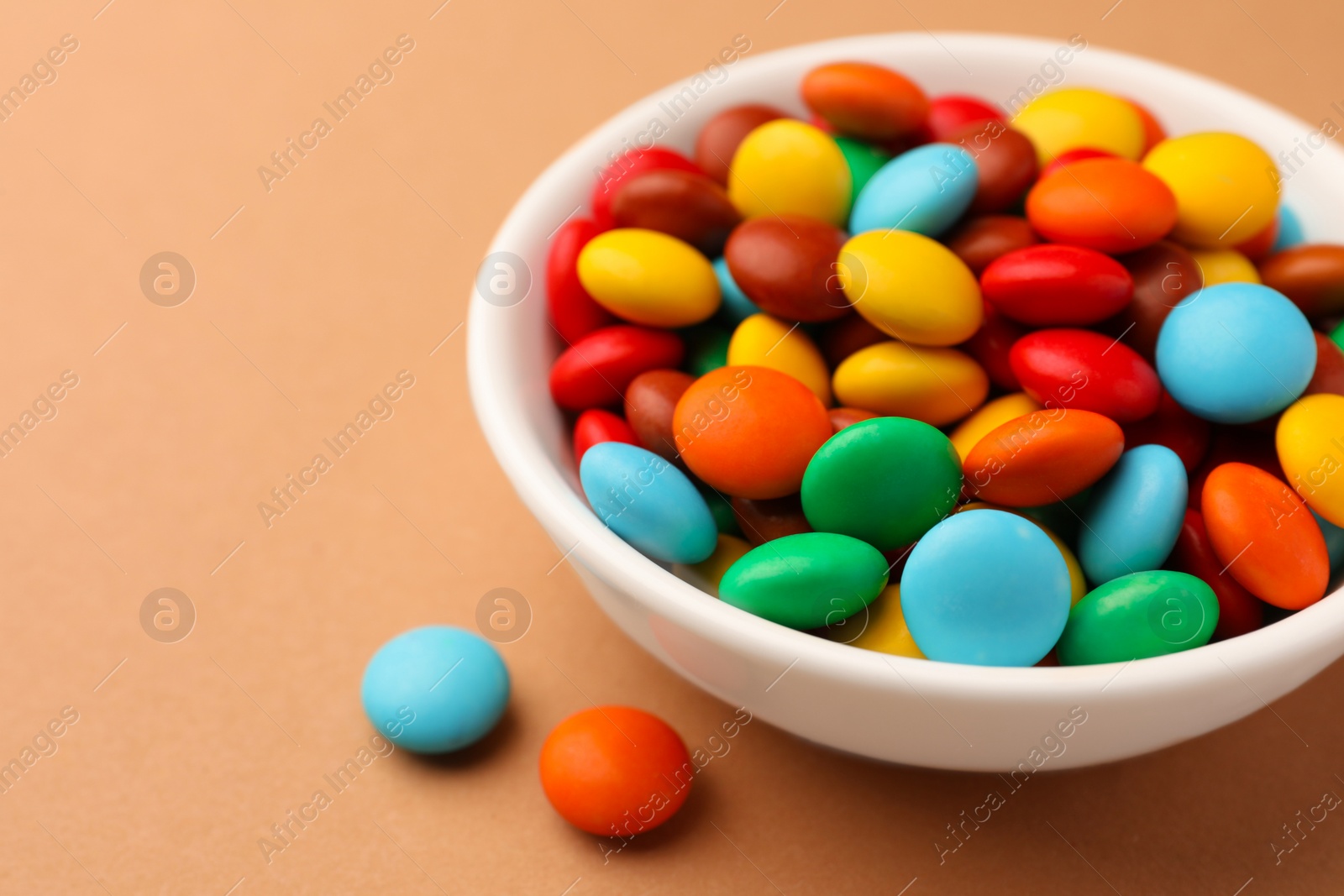 Photo of Tasty colorful candies on light brown background, closeup. Space for text