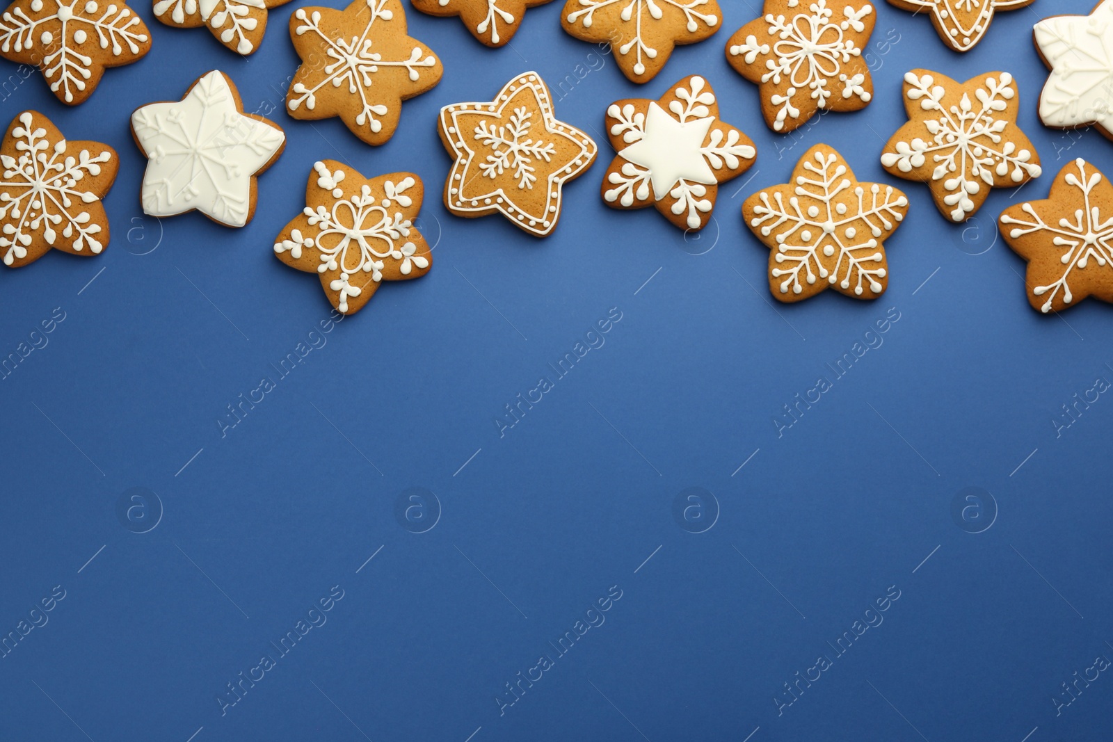 Photo of Tasty star shaped Christmas cookies with icing on blue background, flat lay. Space for text