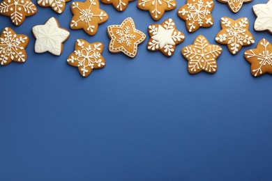 Photo of Tasty star shaped Christmas cookies with icing on blue background, flat lay. Space for text