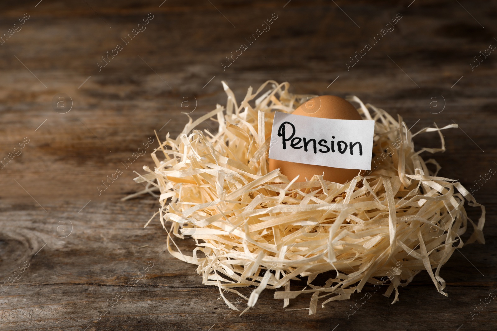 Photo of Egg and card with word PENSION in nest on wooden background