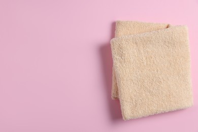 Photo of Soft folded towel on pink background, top view. Space for text