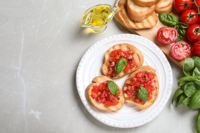 Flat lay composition of tasty bruschettas with tomatoes on light grey marble table, space for text