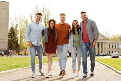 Happy people walking outdoors on sunny day