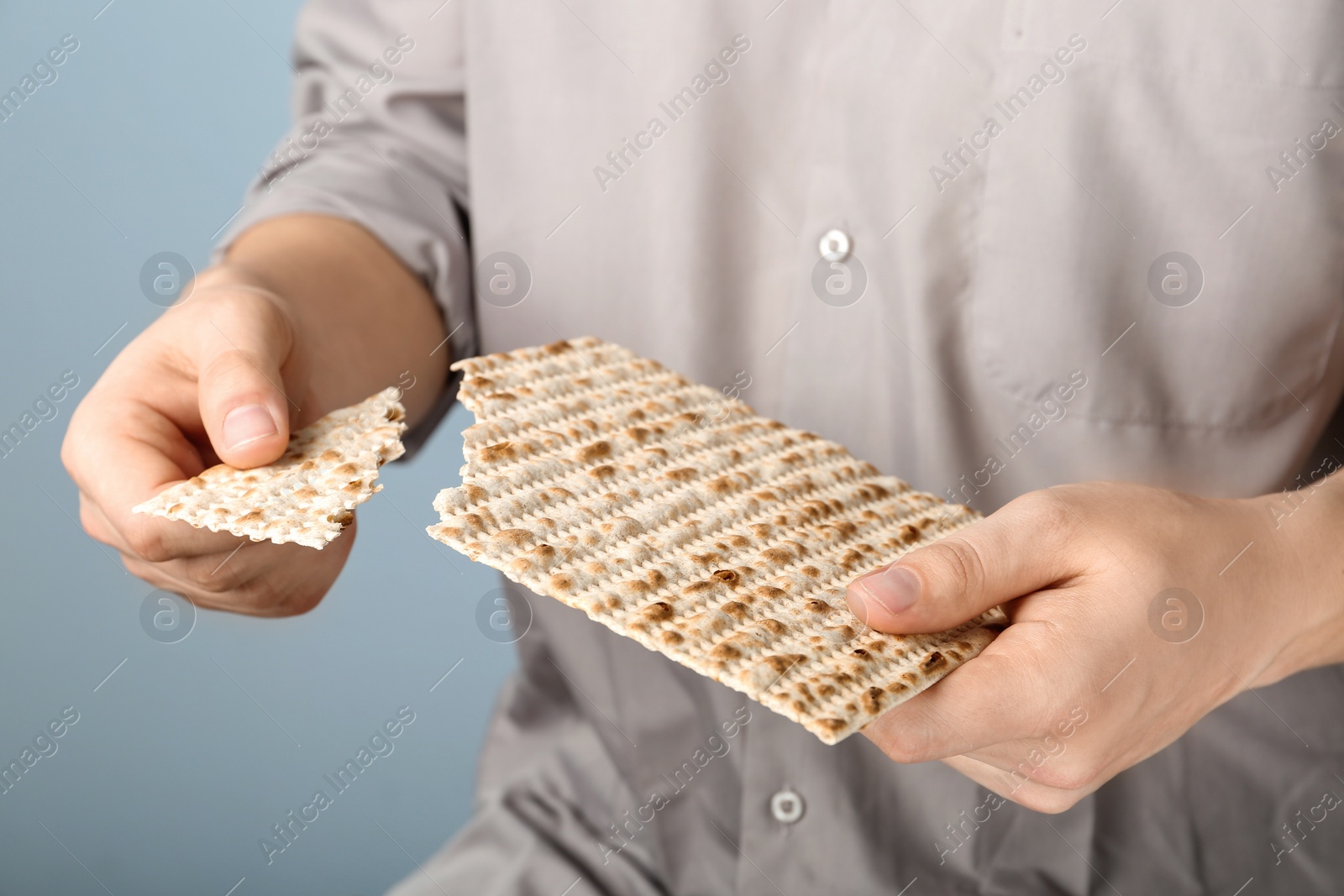 Photo of Man with Matzo on grey background, closeup. Pesach (Passover) celebration