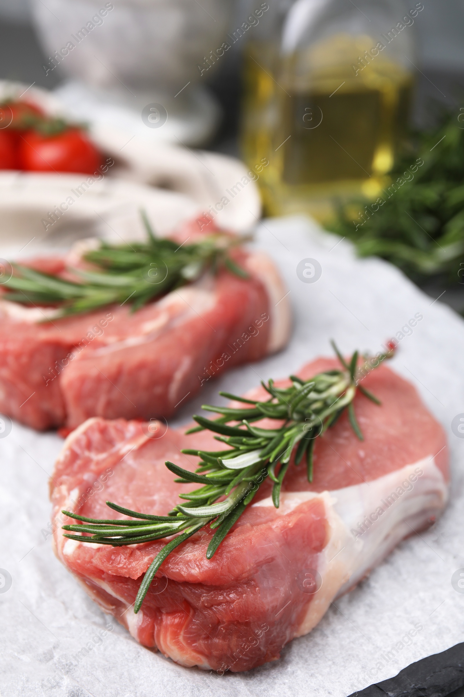 Photo of Fresh raw meat with rosemary on parchment paper, closeup