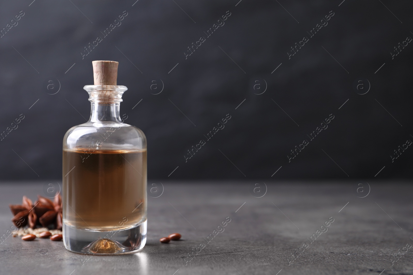 Photo of Anise essential oil and spices on grey table, space for text