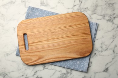 Wooden cutting board and napkin on white marble table, top view. Space for text