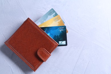 Photo of Credit cards in leather wallet on grey textured table, top view. Space for text