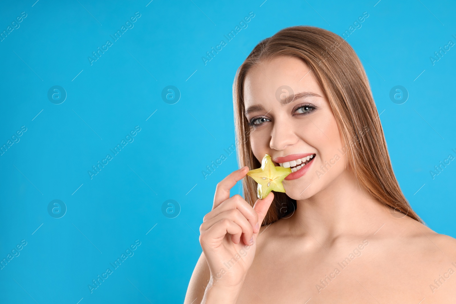 Photo of Young woman with cut carambola on blue background, space for text. Vitamin rich food