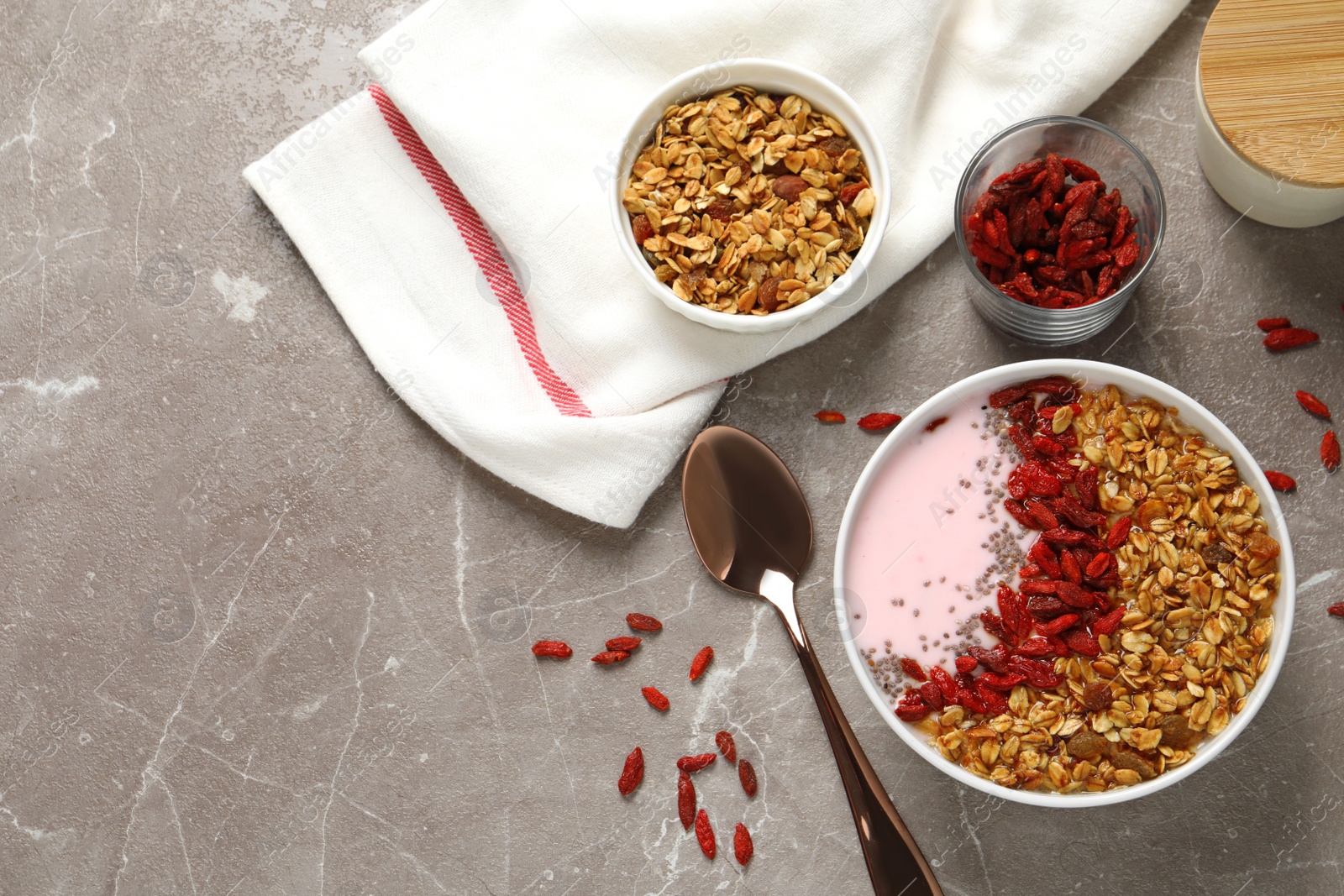 Photo of Flat lay composition of smoothie bowl with goji berries on beige marble table. Space for text