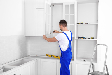 Photo of Worker installing doorcabinet with screwdriver in kitchen