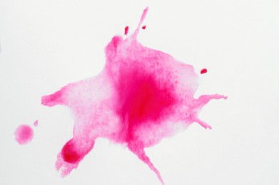 Pink ink blots on white canvas, top view