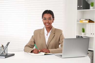 African American intern working at white table in office