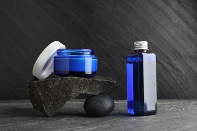 Cosmetic products and stones on grey background