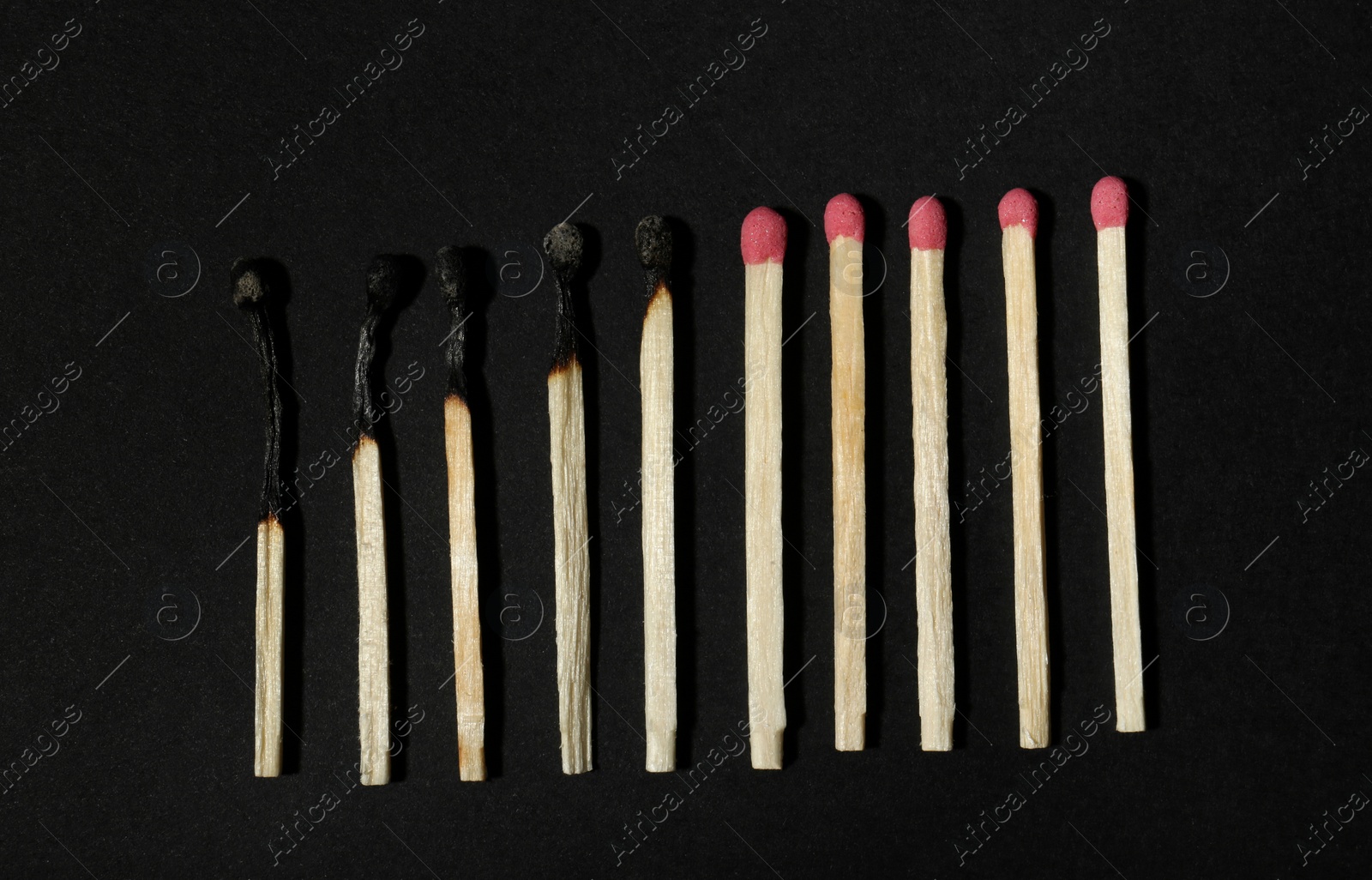 Photo of Burnt and whole matches on black background, flat lay. Stop destruction concept