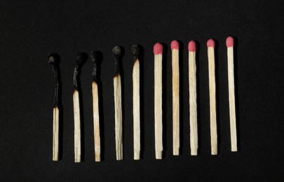 Burnt and whole matches on black background, flat lay. Stop destruction concept