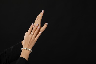 Young woman with elegant pearl jewelry on black background, closeup. Space for text