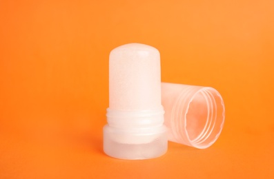 Photo of Natural crystal alum stick deodorant and cap on orange background