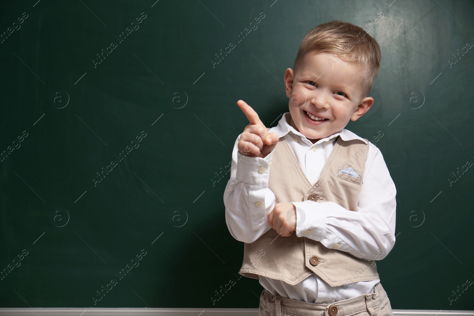 Photo of Funny little child near chalkboard, space for text. First time at school