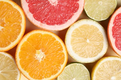 Different cut citrus fruits on beige table, flat lay