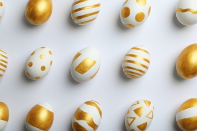 Photo of Flat lay composition of traditional Easter eggs decorated with golden paint on white background