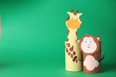 Photo of Toy monkey and giraffe made from toilet paper hubs on green background, space for text. Children's handmade ideas