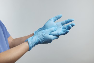 Doctor wearing light blue medical gloves on grey background, closeup