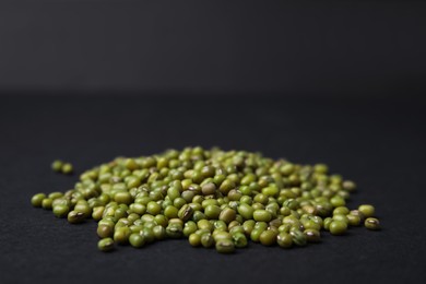 Photo of Pile of green mung beans on black background, closeup. Space for text