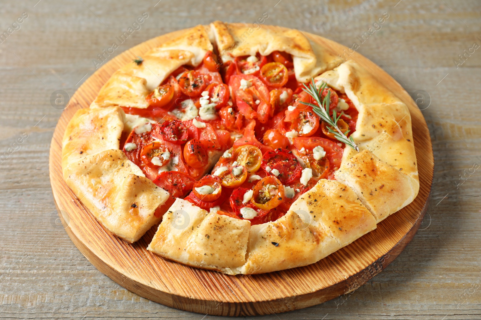 Photo of Tasty galette with tomato, rosemary and cheese (Caprese galette) on wooden table, closeup