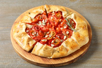 Photo of Tasty galette with tomato, rosemary and cheese (Caprese galette) on wooden table, closeup