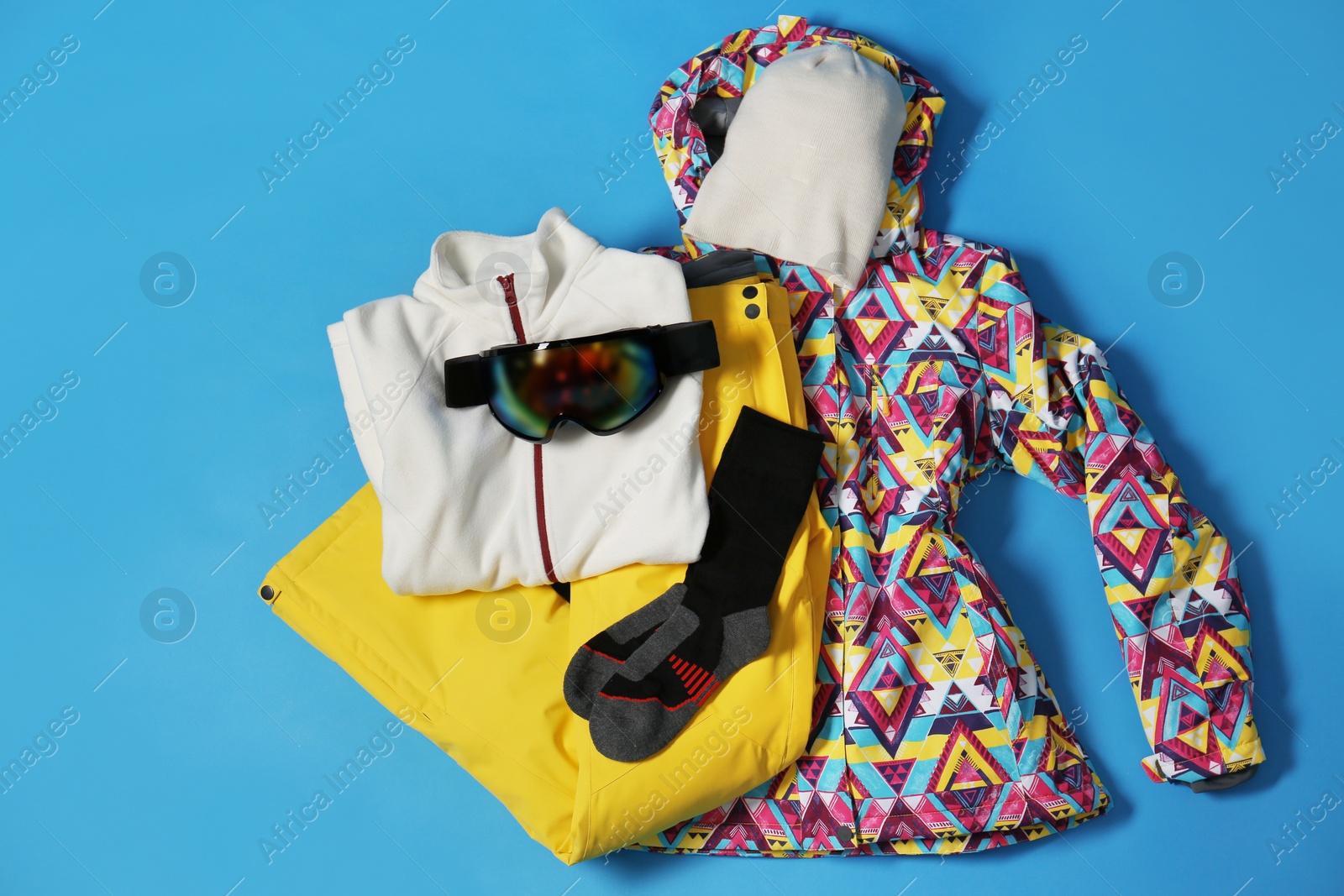 Photo of Stylish winter sport clothes on light blue background, flat lay