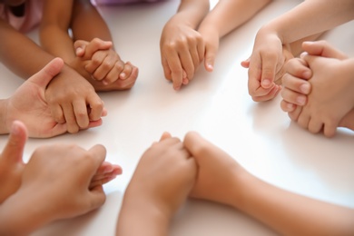 Photo of Little children holding hands at table, closeup. Unity concept