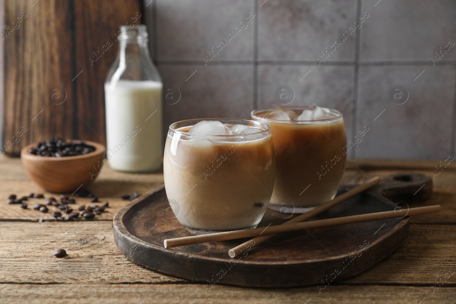 Photo of Refreshing iced coffee with milk in glasses and straws on wooden table