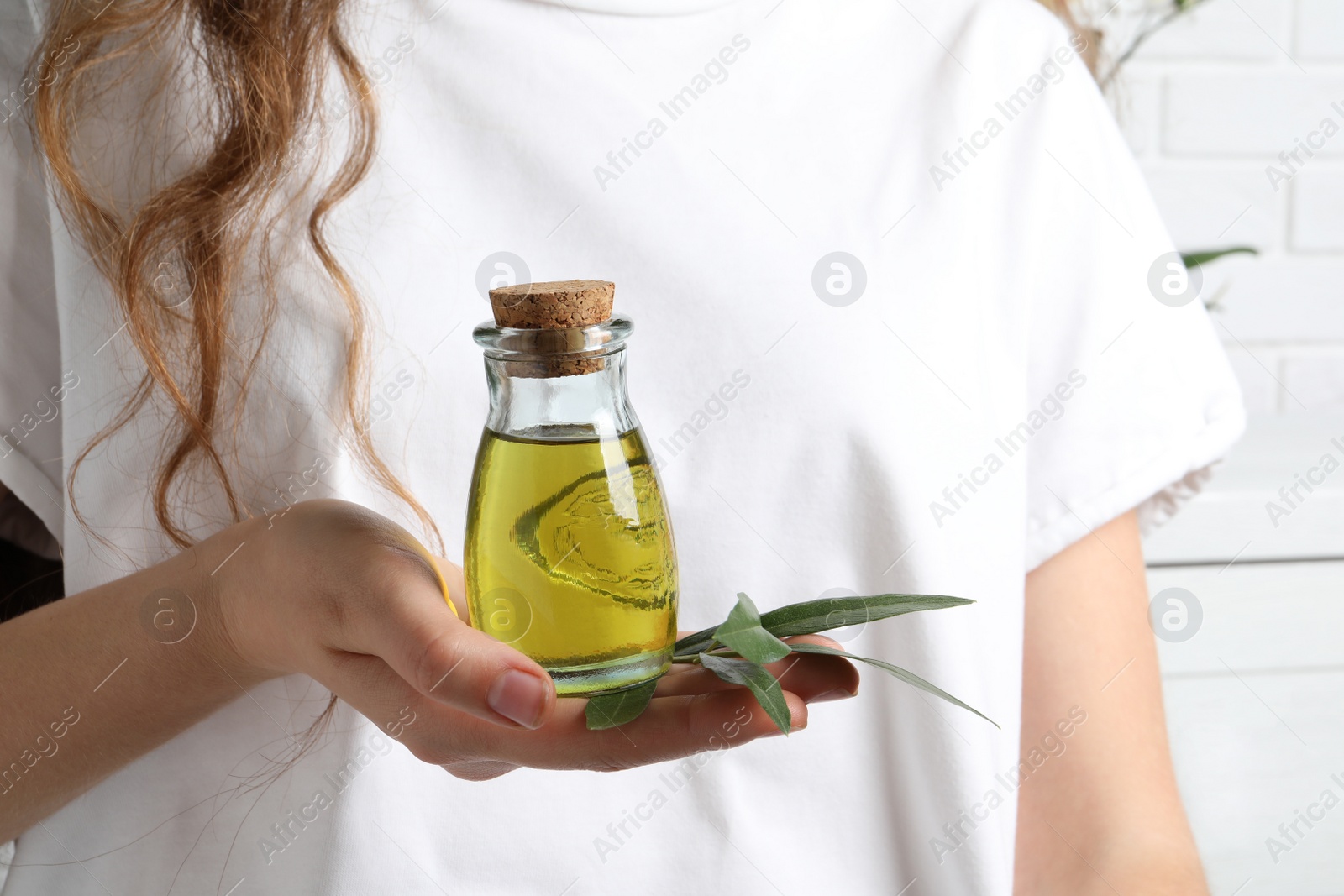 Photo of Young woman holding bottle of fresh olive oil, closeup