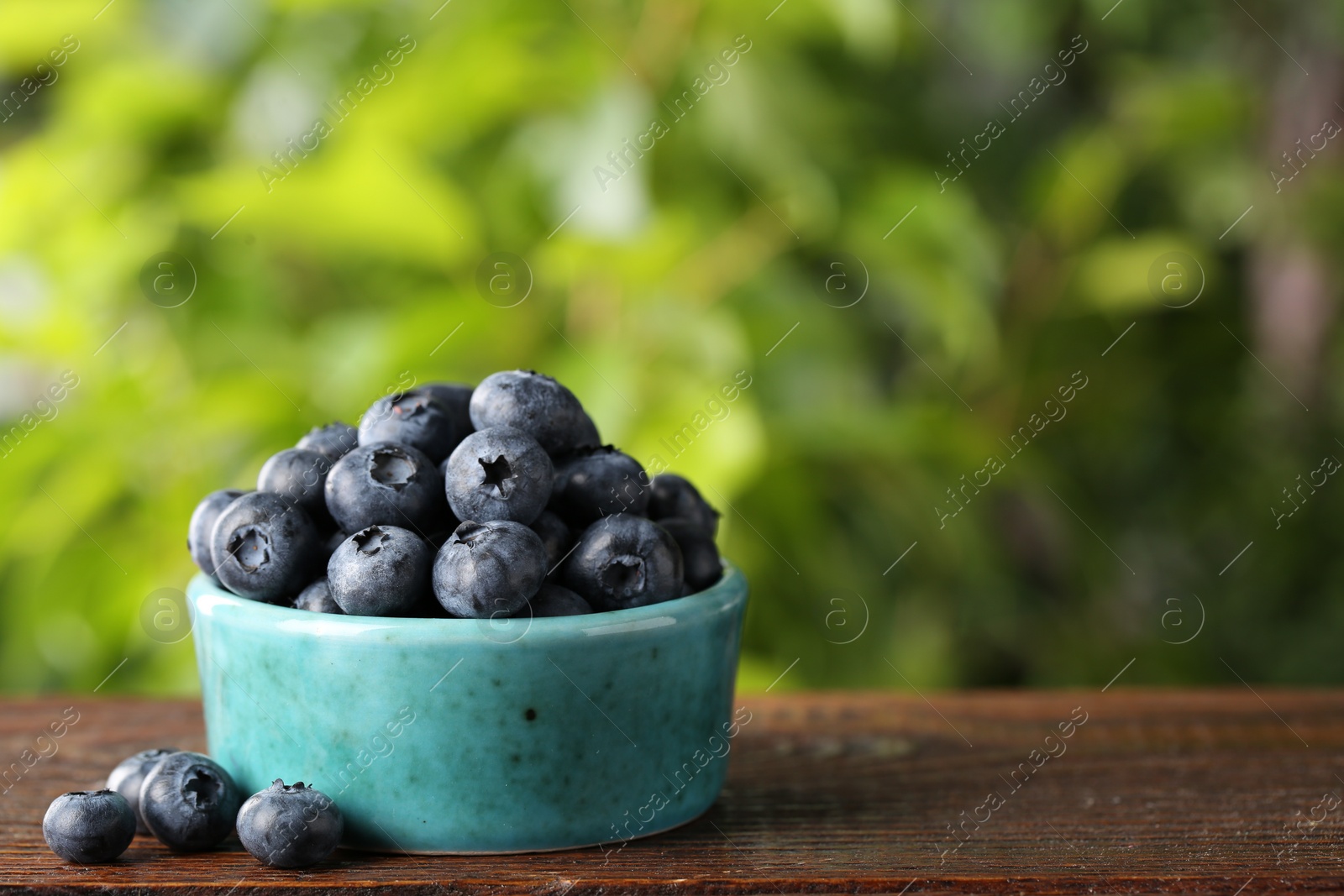 Photo of Tasty fresh blueberries on wooden table outdoors, space for text