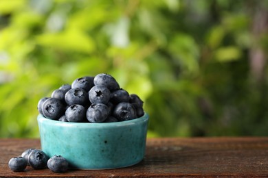 Tasty fresh blueberries on wooden table outdoors, space for text