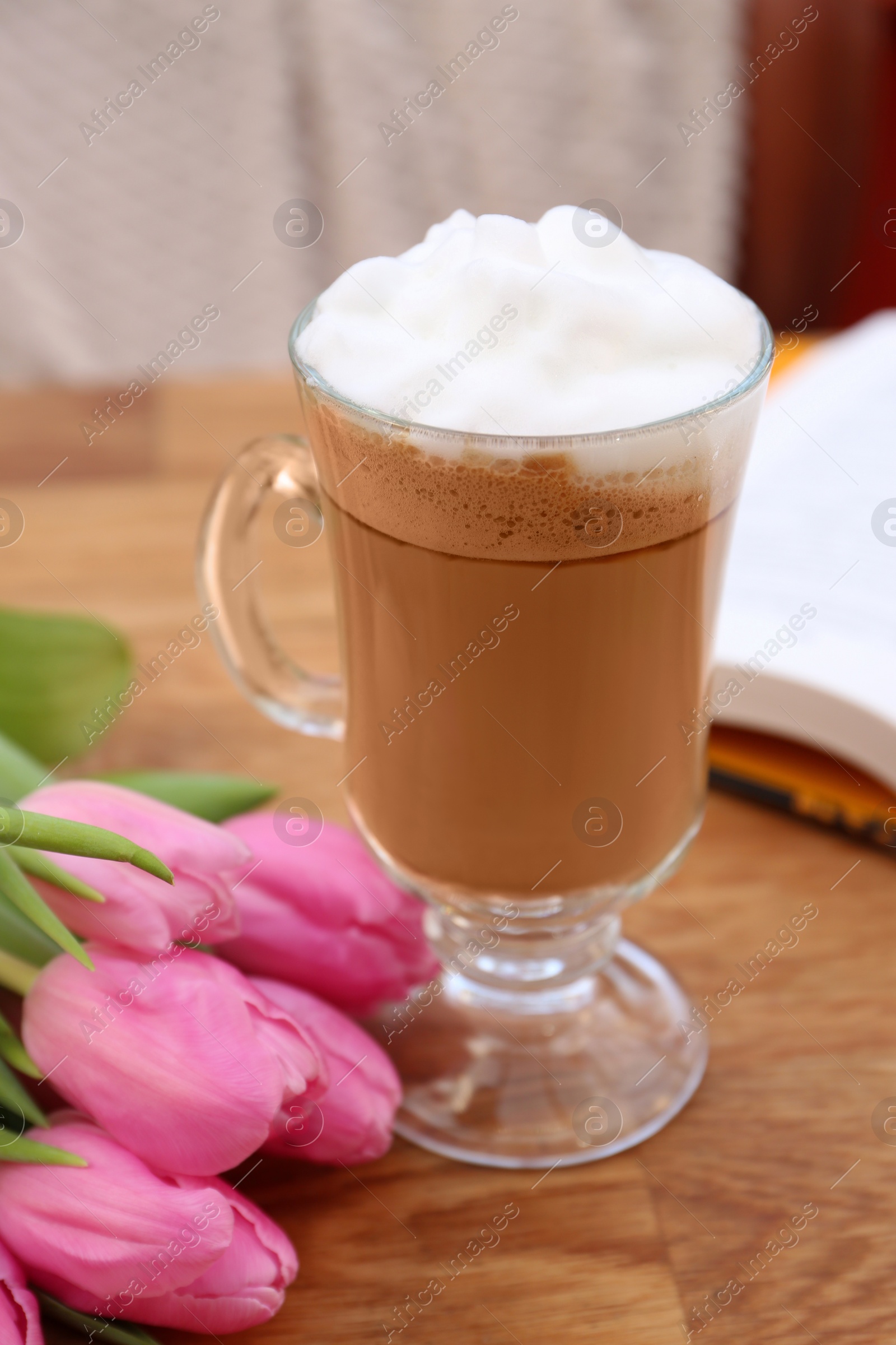 Photo of Glass of delicious cocoa and pink tulips on wooden table