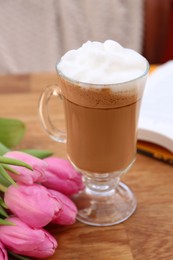 Photo of Glass of delicious cocoa and pink tulips on wooden table
