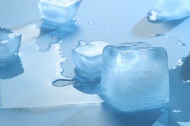Photo of Crystal clear ice cubes on light blue background