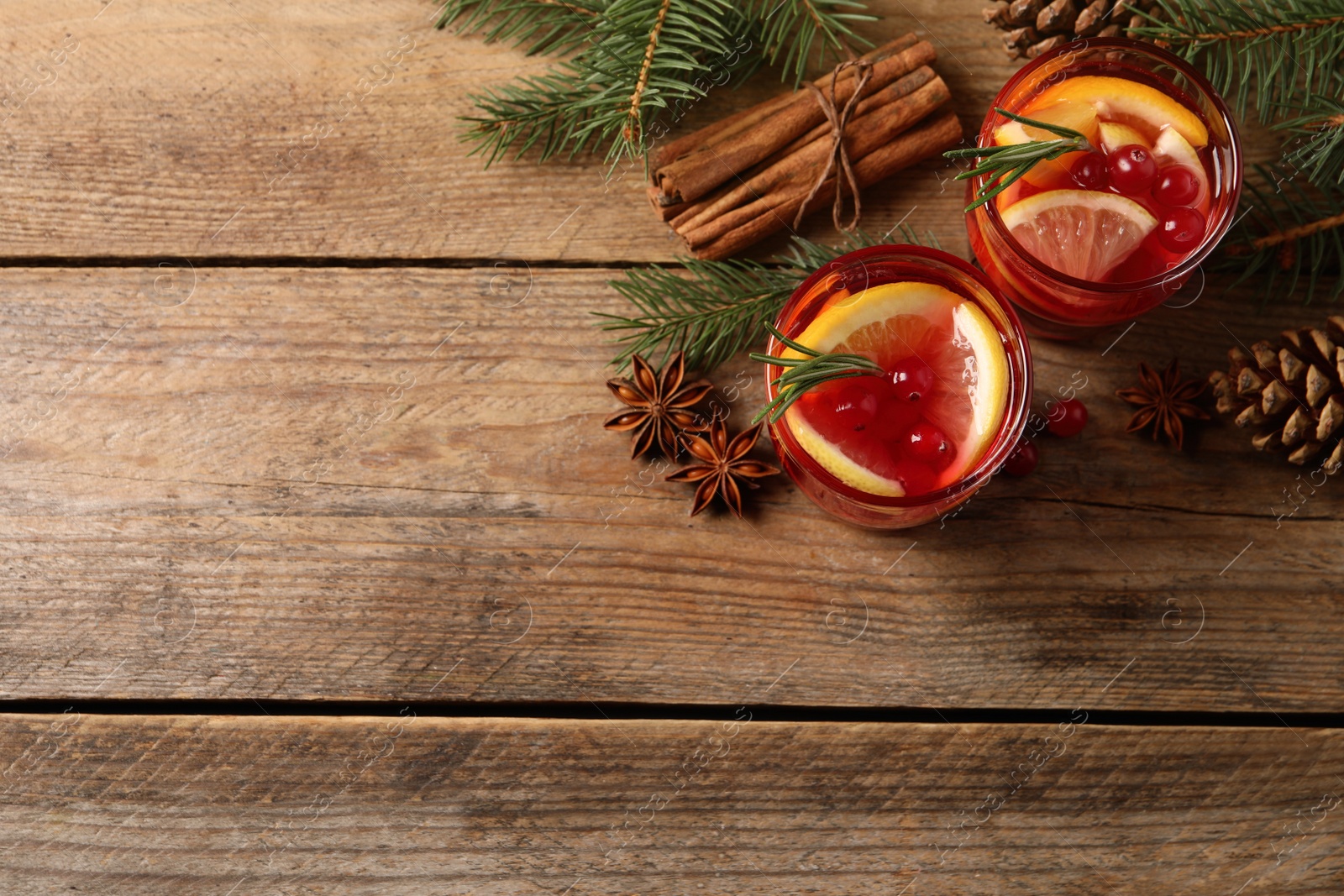 Photo of Delicious punch drink with cranberries, orange and spices on wooden table, flat lay. Space for text